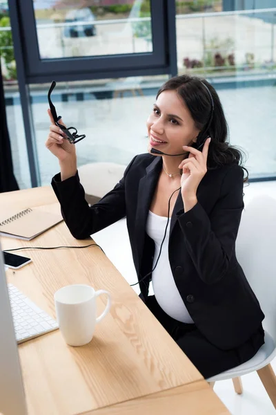 Mujer de negocios embarazada con auriculares call center - foto de stock