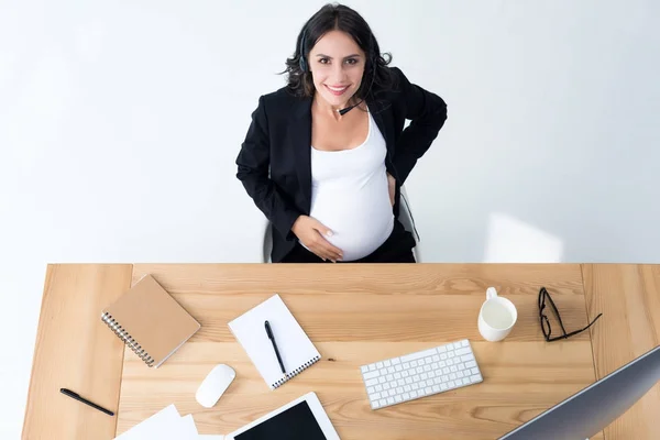 Mujer de negocios embarazada con auriculares call center - foto de stock