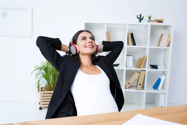 Embarazada mujer de negocios relajarse y escuchar música - foto de stock