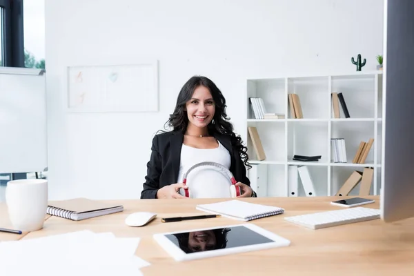 Pregnant businesswoman with headphones on tummy — Stock Photo