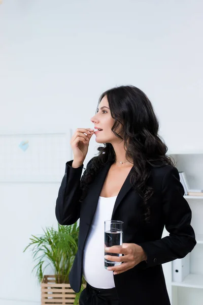 Pregnant businesswoman taking pill — Stock Photo