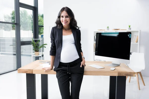 Mulher de negócios grávida inclinando-se para trás na mesa de trabalho — Fotografia de Stock