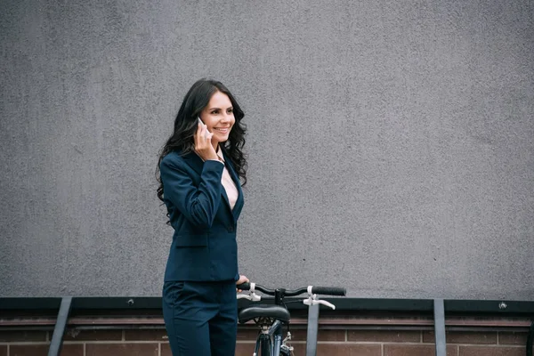Businesswoman with bicycle talking by phone — Stock Photo
