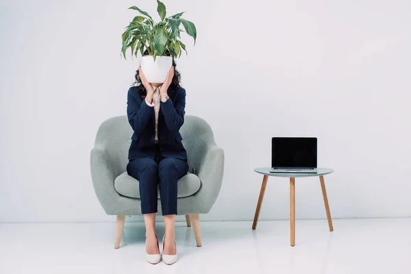 Business woman covering face with flower pot — стоковое фото