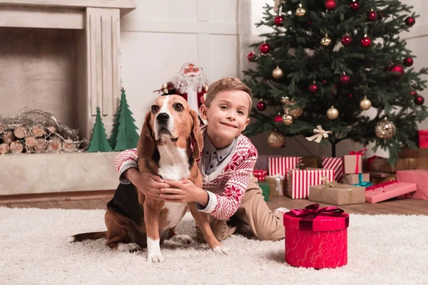 Boy embracing beagle dog on christmas — Stock Photo