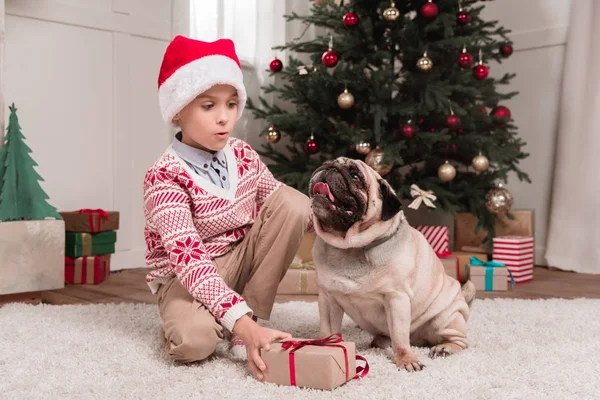 Garçon avec cadeau de Noël et carlin — Photo de stock