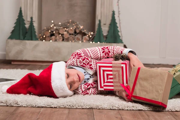 Boy laying on floor with christmas gifts — Stock Photo