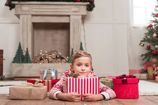 Junge liegt mit Weihnachtsgeschenken auf dem Boden — Stockfoto