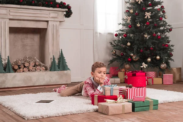 Junge liegt mit Weihnachtsgeschenken auf dem Boden — Stockfoto