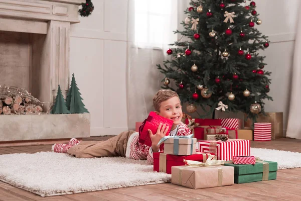 Хлопчик лежить на підлозі з різдвяними подарунками — стокове фото