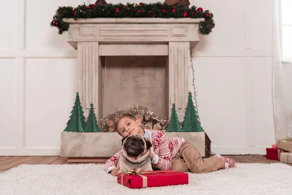 Garçon avec cadeau de Noël et carlin — Photo de stock