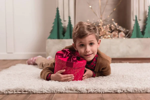 Niño tendido en el suelo con regalo - foto de stock