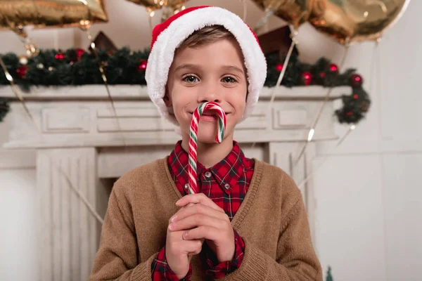 Хлопчик у капелюсі Санта з цукерковою тростиною — стокове фото