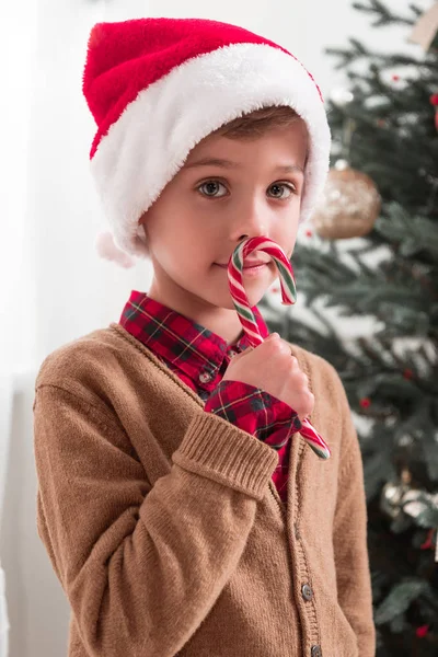 Niño en sombrero de santa con bastón de caramelo - foto de stock