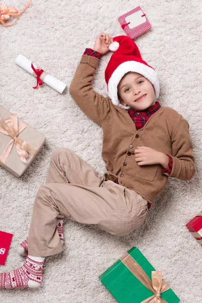 Niño en la alfombra con regalos de Navidad - foto de stock