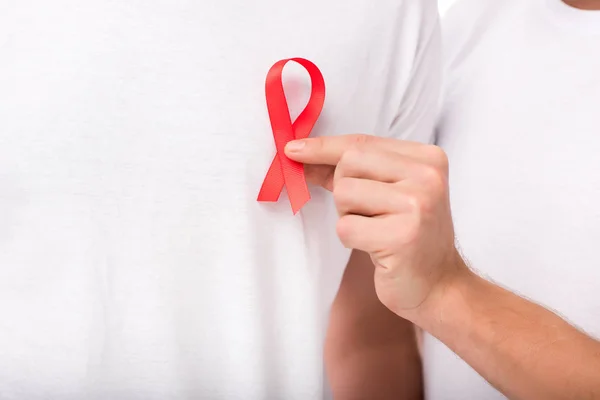 Man attaching aids ribbon on t-shirt — Stock Photo