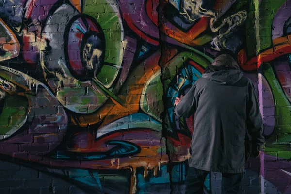 Straßenkünstler malt nachts Graffiti mit Aerosolfarbe an Wand — Stockfoto