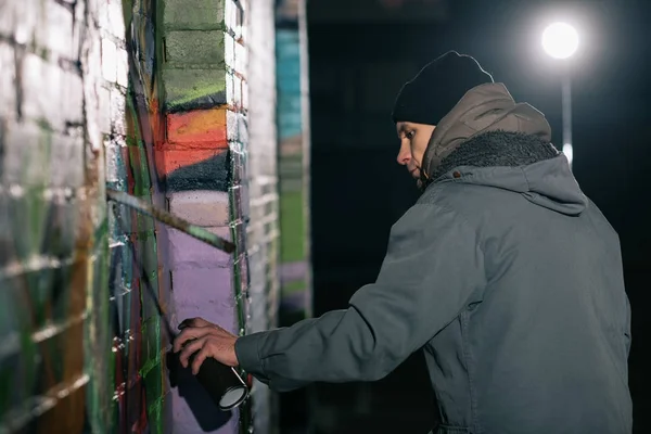 Straßenkünstler bemalt nachts Graffiti mit Aerosolfarbe an Wand — Stockfoto