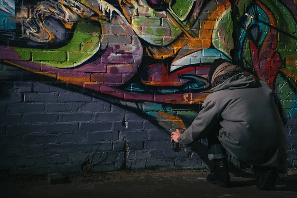 Rückansicht eines Straßenkünstlers, der nachts Graffiti mit Aerosolfarbe an Wand malte — Stockfoto