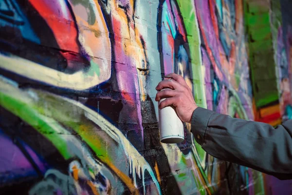 Cropped view of street artist painting graffiti with aerosol paint on wall at night — Stock Photo