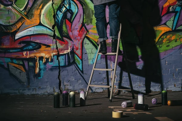 Vue recadrée de debout sur échelle et peinture graffiti coloré la nuit — Photo de stock