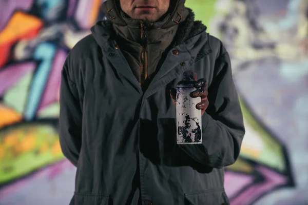 Vista ritagliata di uomo che tiene lattina con vernice aerosol di notte — Foto stock