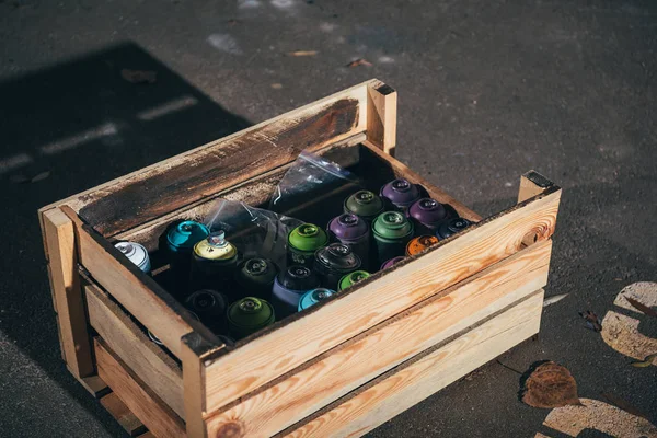 Cans with aerosol paint in wooden box — Stock Photo