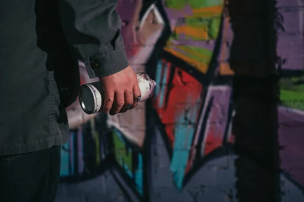 Cropped view of street artist painting graffiti with aerosol paint on wall at night — Stock Photo