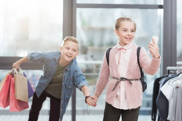 Bambini felici con borse della spesa che fanno selfie al negozio — Foto stock