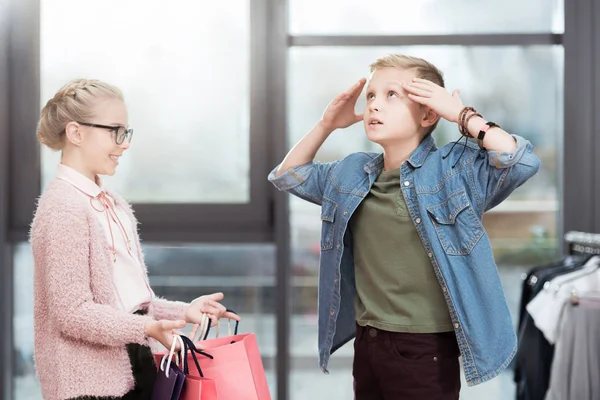 Kid holding paper bags in hands against tired boy at shop — Stock Photo