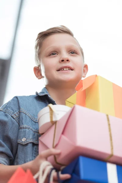 Lächelnder Junge mit gestapelten Kisten mit Papiertüten in der Hand im Geschäft — Stockfoto