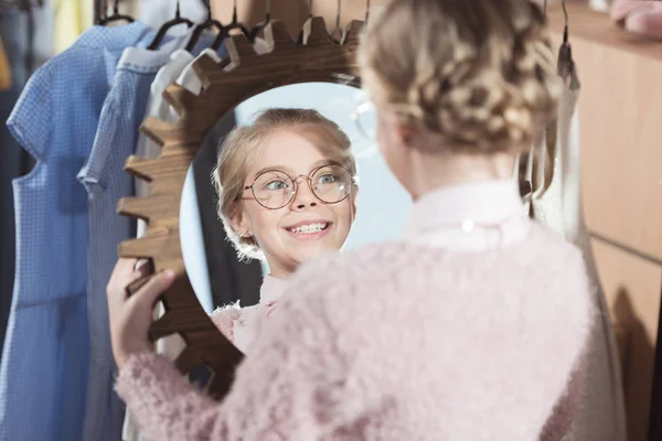 Bambino sorridente guardando specchio nelle sue mani al negozio interno — Foto stock