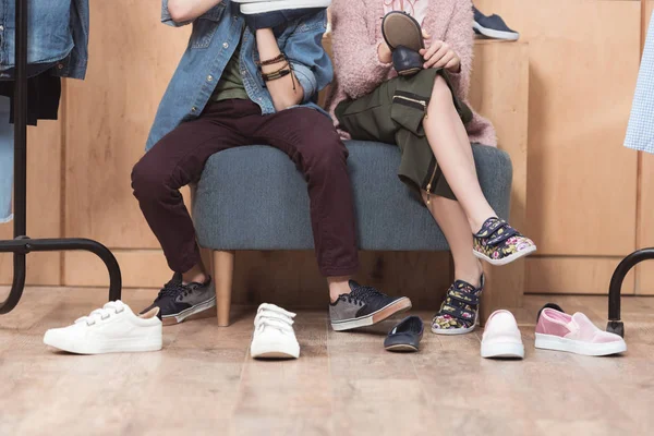 Cropped image of kids sitting on sofa surrounded by scattered shoes on floor — Stock Photo