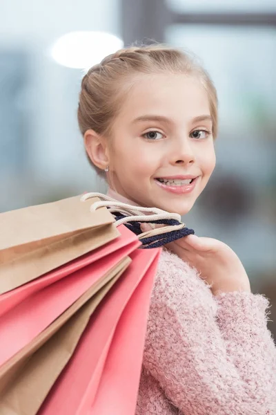 Happy kid looking at camera and holding paper bags in hand — Stock Photo