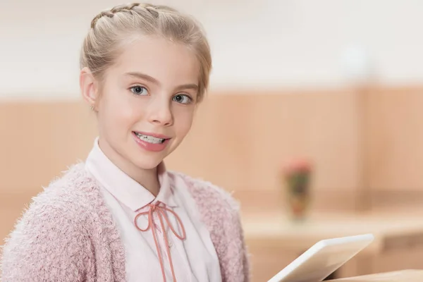 Smiling child with digital tablet looking at camera at cafe — Stock Photo