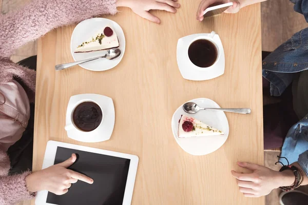 Cropped image of children sitting at table with gadgets on surface at cafe — Stock Photo
