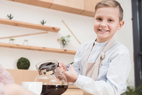 Garçon souriant tenant pot avec café dans les mains au café — Photo de stock