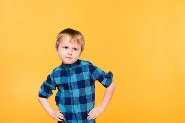 Retrato de niño pequeño en camisa de pie akimbo aislado en amarillo - foto de stock