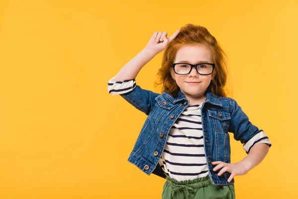 Retrato de menino bonito em óculos de pé akimbo isolado em amarelo — Fotografia de Stock