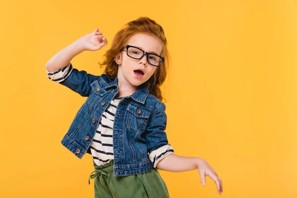 Ritratto di bambino carino in occhiali che balla isolato su giallo — Foto stock