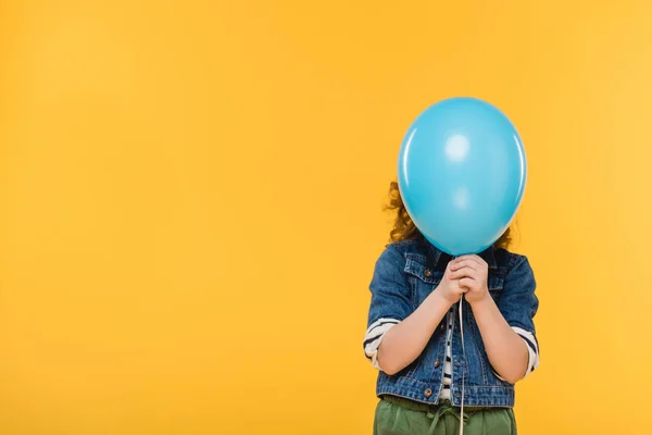 Vista oscurata del bambino che copre il viso con palloncino isolato sul giallo — Foto stock