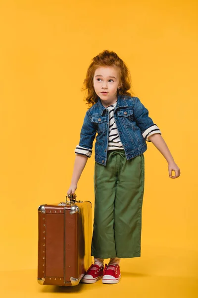 Elegante niño sosteniendo maleta aislada en amarillo — Stock Photo