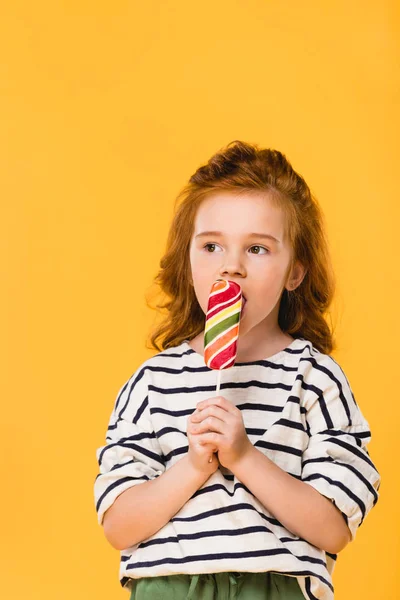 Retrato de pré-adolescente criança comer pirulito isolado no amarelo — Fotografia de Stock