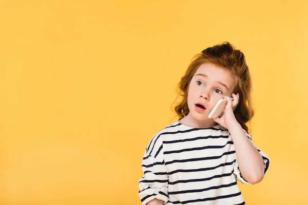 Retrato de niño lindo hablando en el teléfono inteligente aislado en amarillo - foto de stock