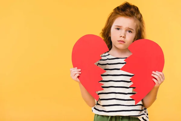 Portrait of sad child with broken red paper heart isolated on yellow, st valentines day concept — Stock Photo