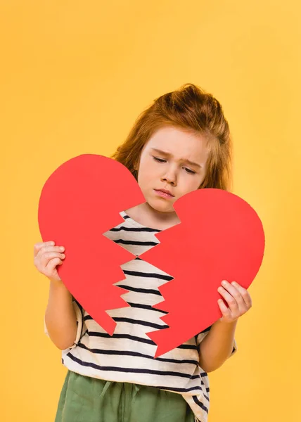 Portrait d'enfant triste avec un coeur en papier rouge brisé isolé sur jaune, concept St Valentin — Photo de stock
