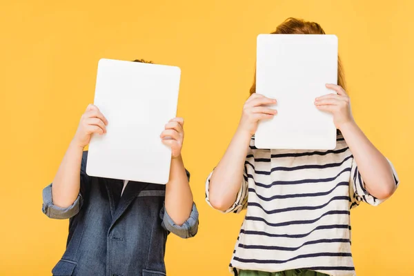 Obscured view of kids holding tablets isolated on yellow — Stock Photo