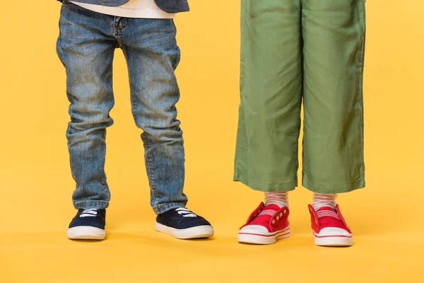 Vista parcial de los niños con ropa casual aislada en amarillo - foto de stock