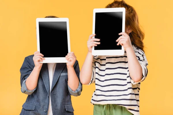 Vista oscurata di bambini che tengono compresse con schermi vuoti isolati su giallo — Foto stock