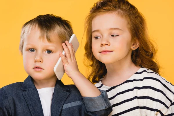 Ritratto di bambino che parla su smartphone con amico vicino isolato su giallo — Foto stock